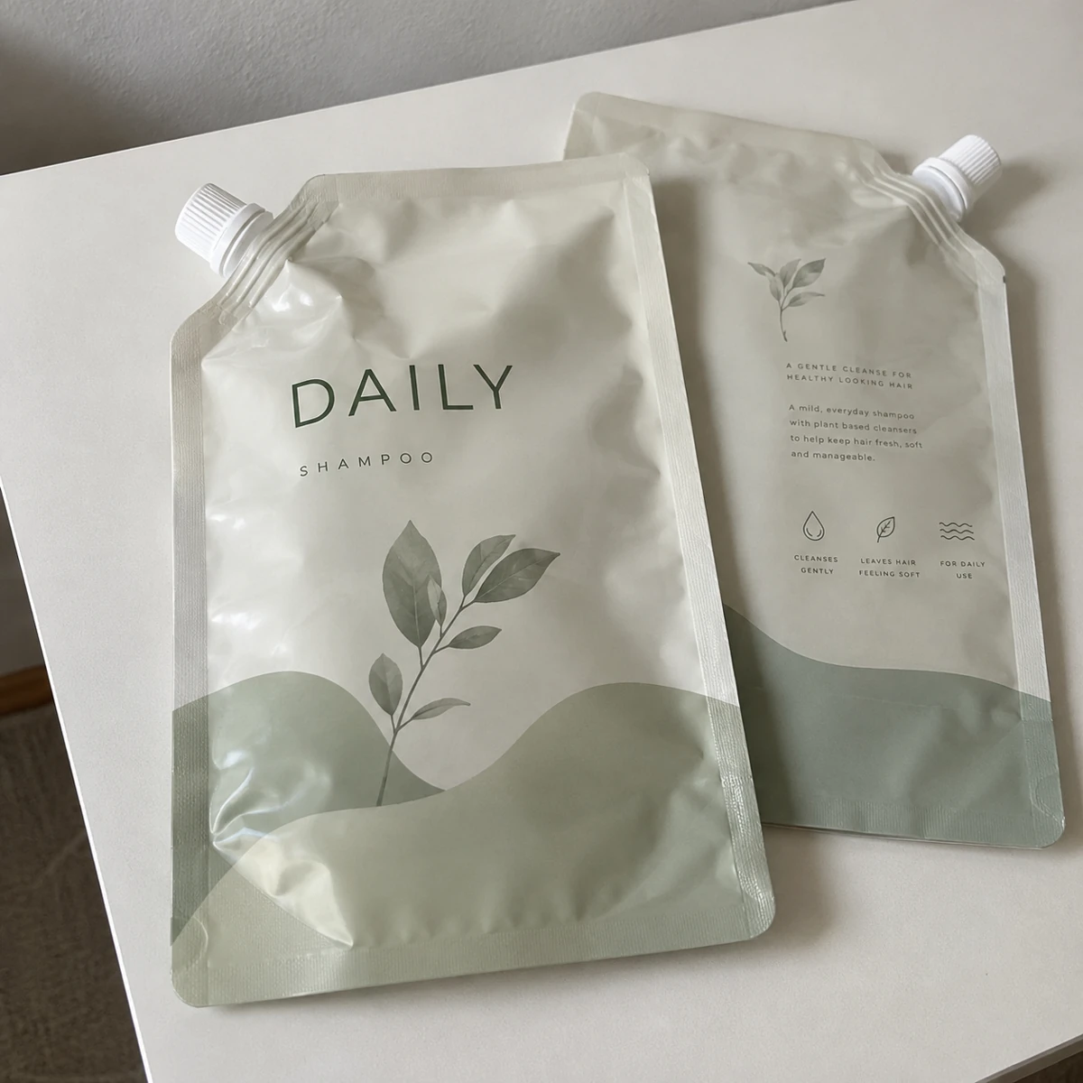 Empty spout pouches sample with shampoo refill artwork, fully displayed on a table